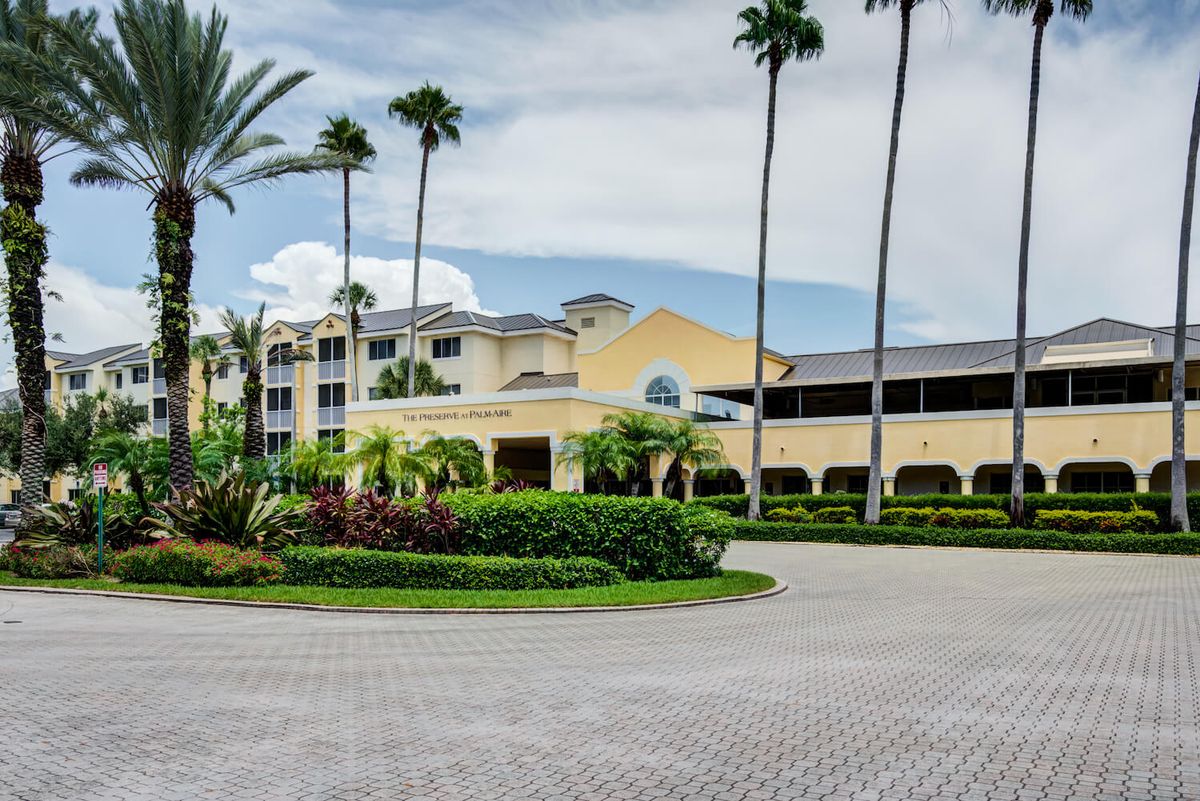 A luxurious hotel surrounded by palm trees and well-maintained landscaping.