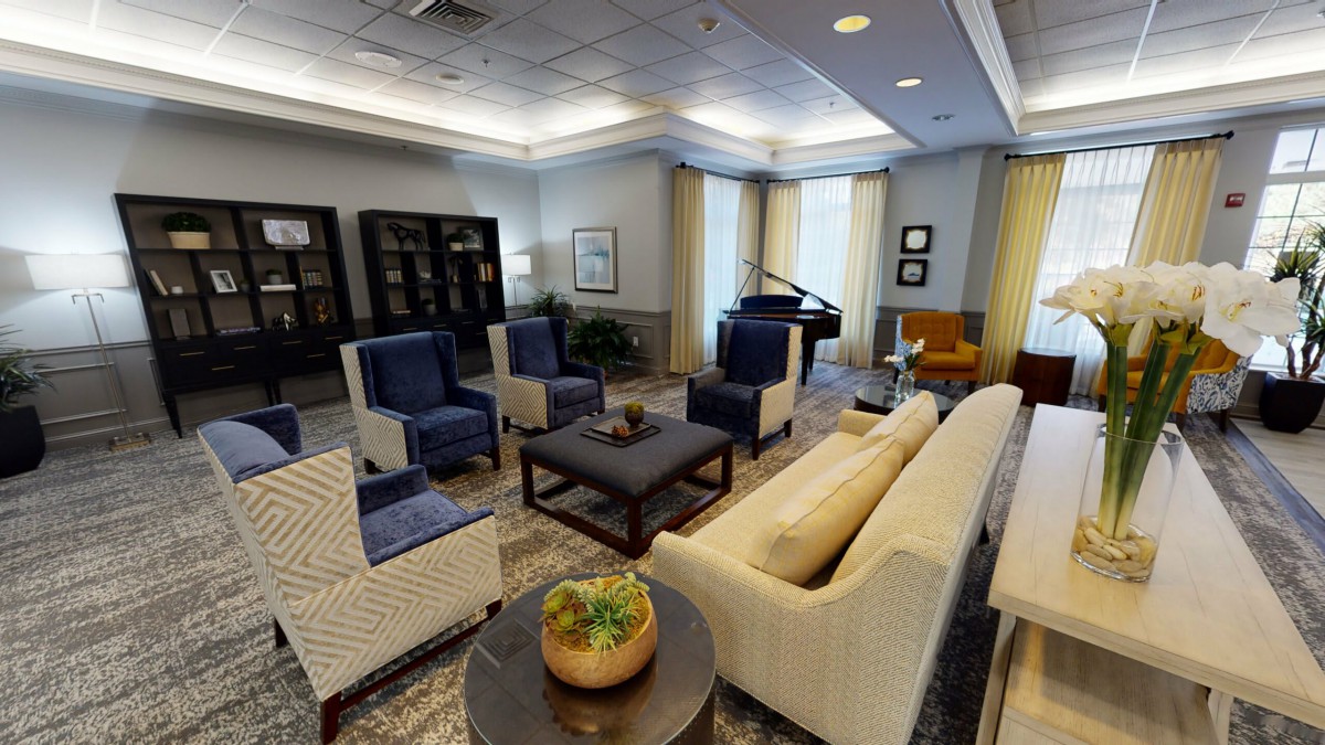 A modern living room with comfortable seating and stylish decor, featuring a piano and decorative plants.