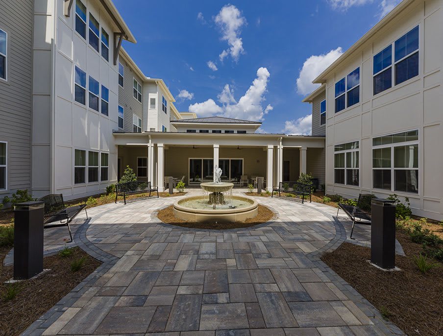 A courtyard with a central fountain surrounded by a residential building under a clear blue sky.