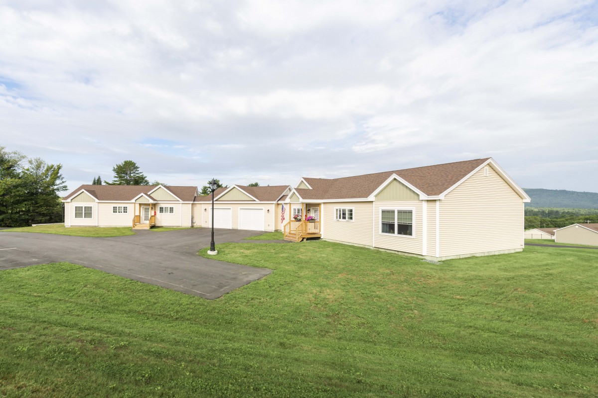A row of single-story homes with well-maintained lawns in a suburban neighborhood.