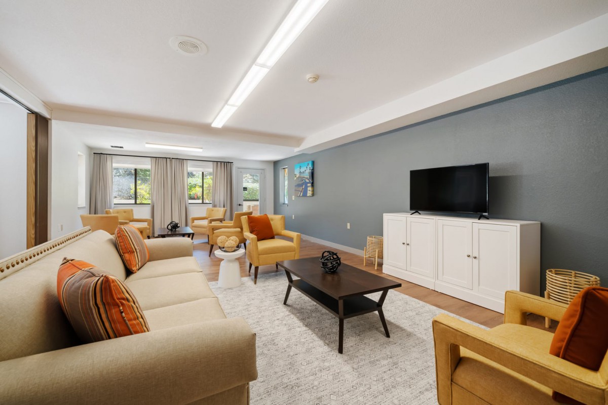 A modern living room with neutral tones, featuring comfortable sofas, armchairs, a coffee table, and a television on a sleek cabinet.