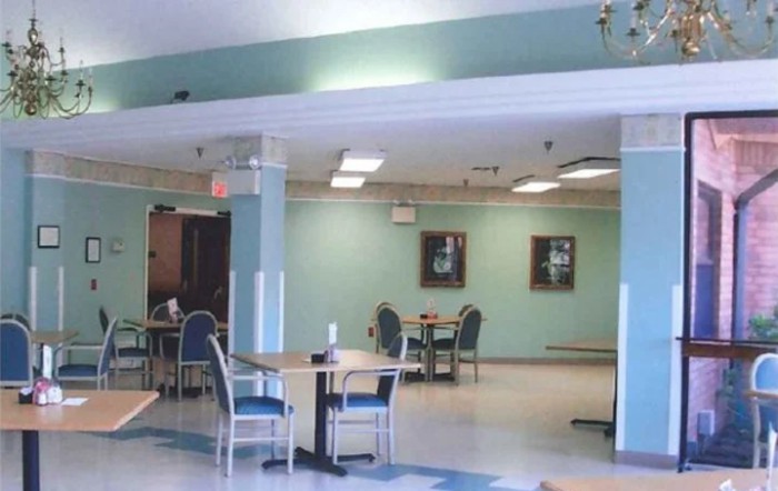 A spacious dining area with tables and chairs, featuring soft lighting and wall decor.