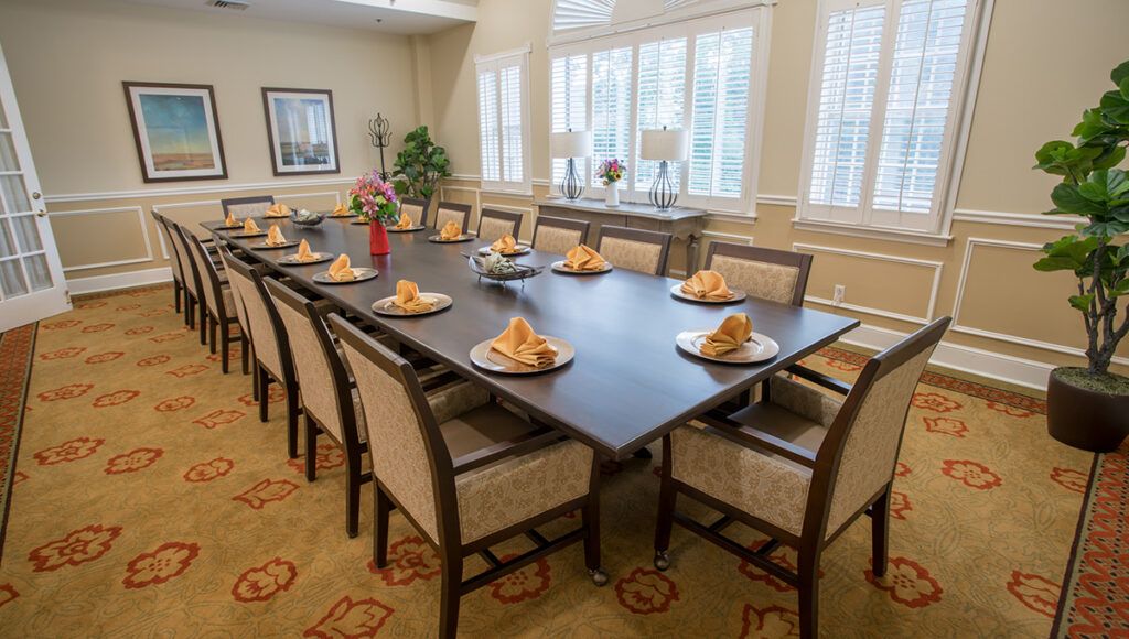 A well-appointed dining room with a large table set for a formal gathering, featuring elegant chairs and neatly placed napkins.