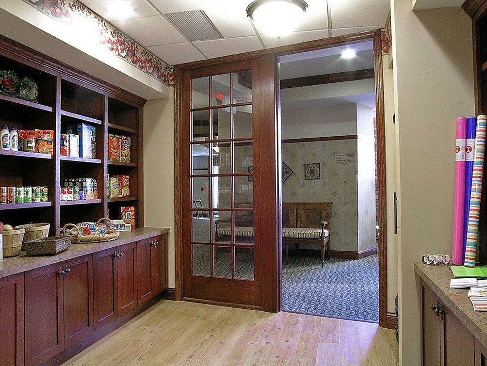 A cozy office lobby with wooden furnishings and a bookshelf, leading to another room.