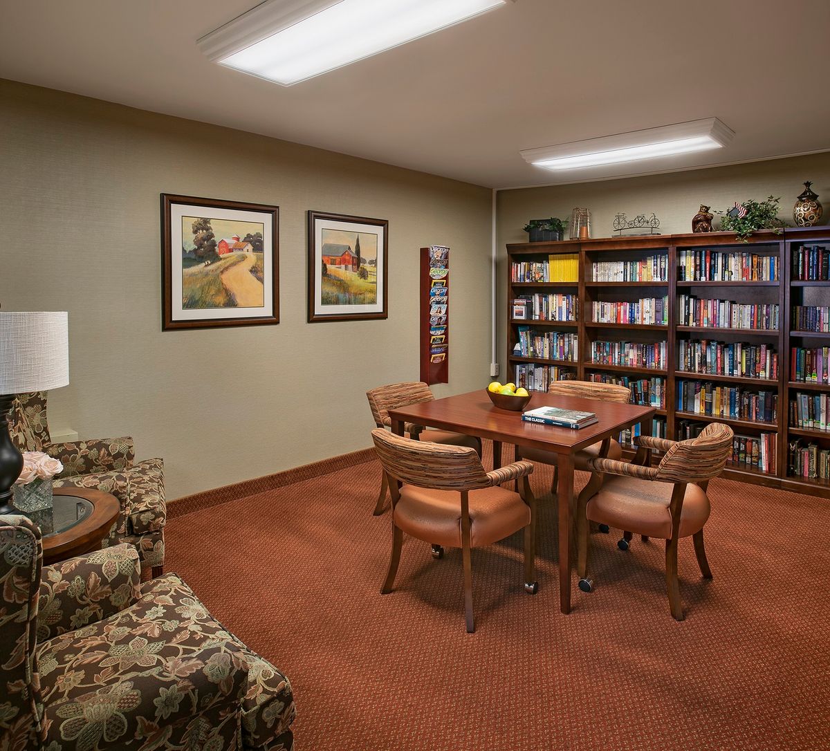 Cozy reading room with a table, chairs, and a bookshelf filled with books.