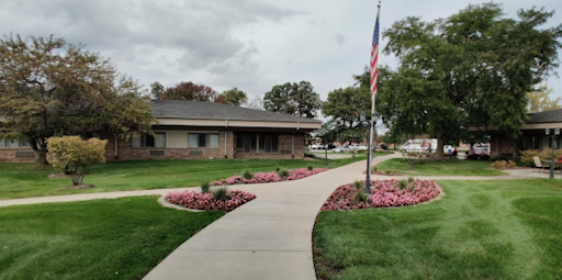 A serene view of a landscaped area with a building and flag, showcasing a well-maintained garden.