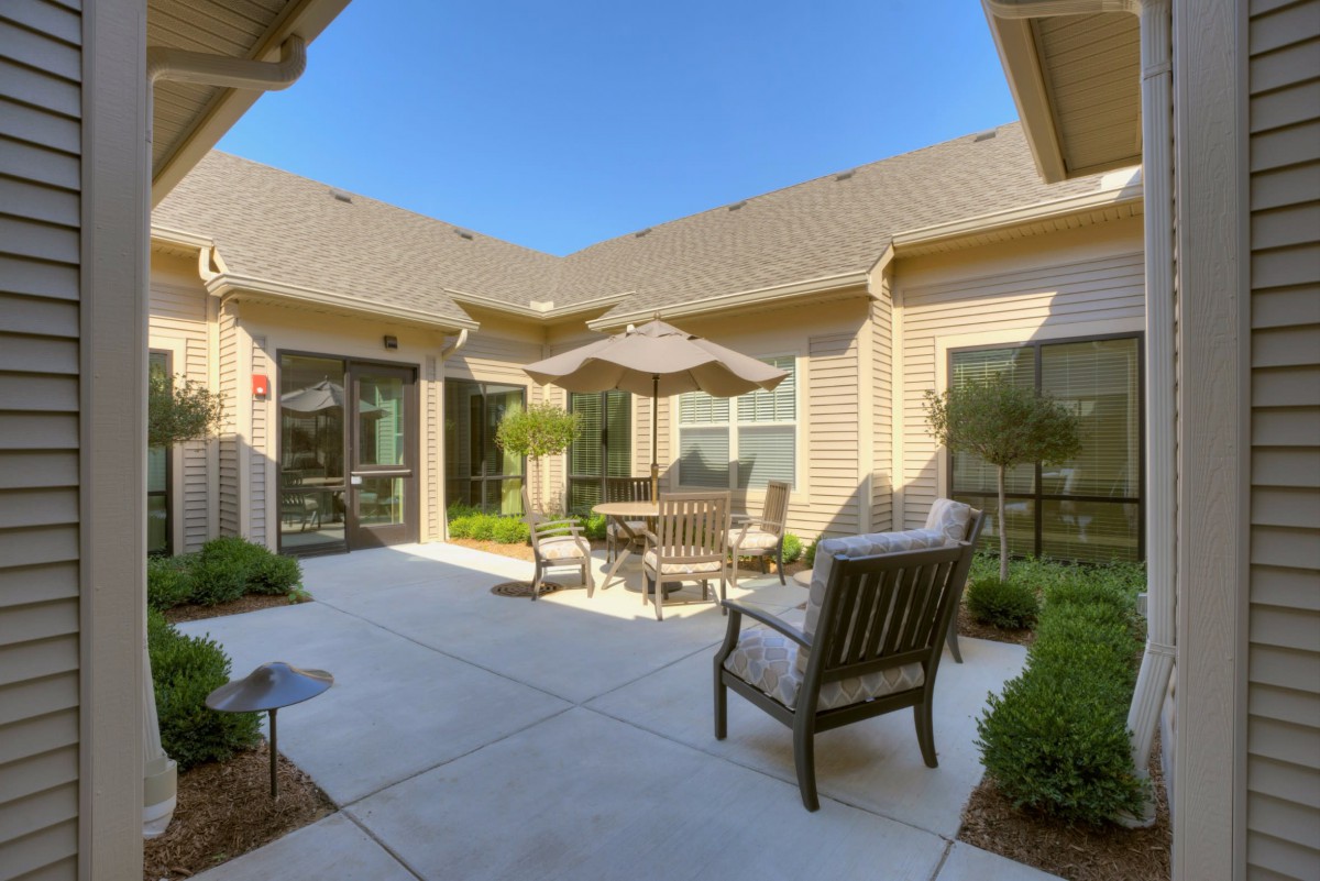 A cozy courtyard with outdoor seating and an umbrella on a sunny day.