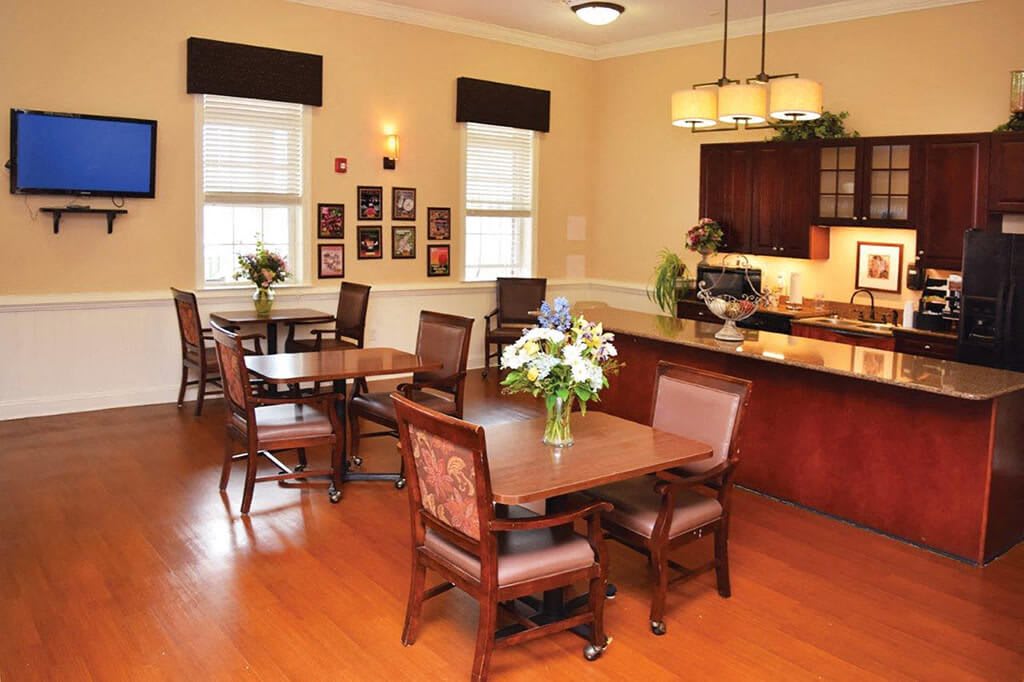 A cozy dining area with neatly arranged tables and chairs, featuring a warm and inviting decor with floral centerpieces.