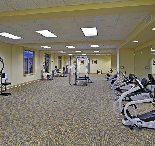 An empty gym with various exercise equipment including cardio machines and weights.