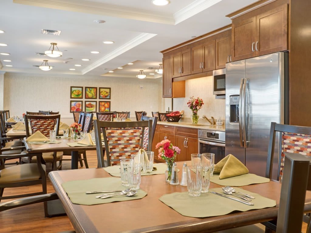 A modern dining area with elegantly set tables and contemporary kitchen appliances.