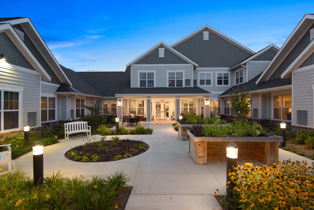 A well-lit residential courtyard with landscaped gardens in the evening.