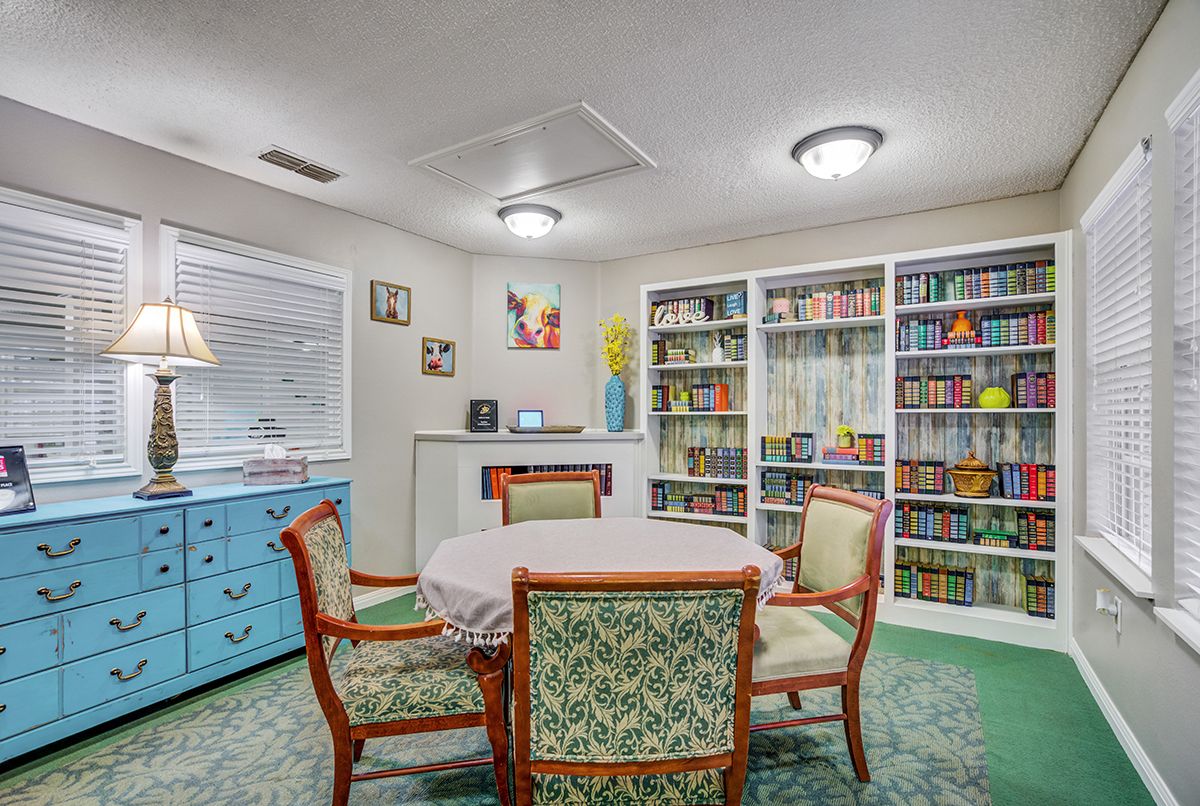 A cozy room with a round table, surrounded by chairs and bookshelves filled with books.