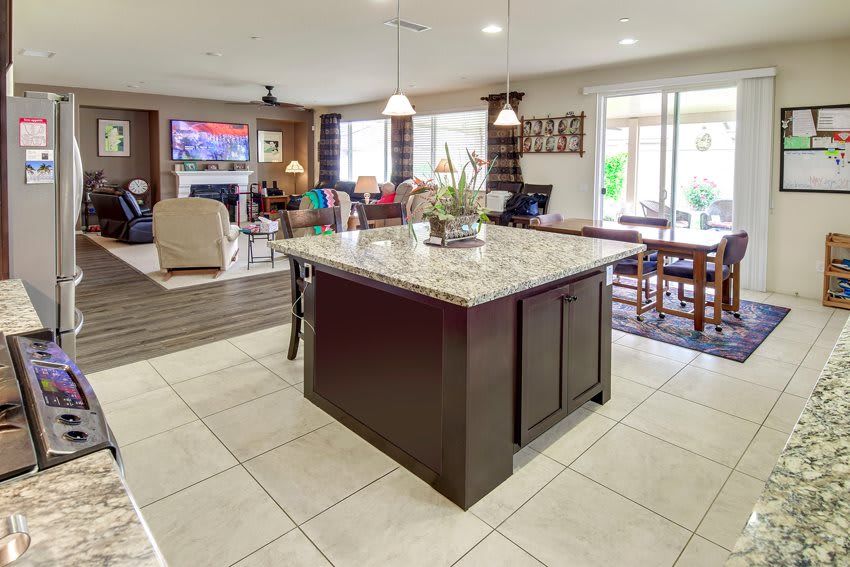 A modern kitchen with a granite island and open floor plan leading to the living and dining areas.