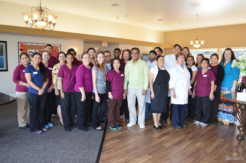 A group photo of employees posing together indoors at their workplace.