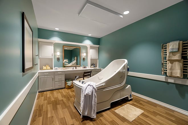 A tranquil spa room with a massage table and calming teal walls.