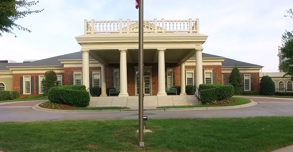 A building with classical architecture featuring columns and a flagpole in front.