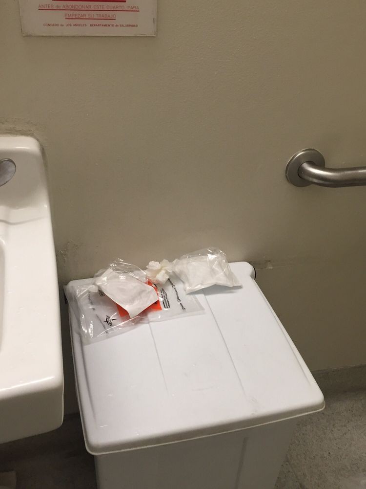Bathroom with paper products and trash on toilet tank.