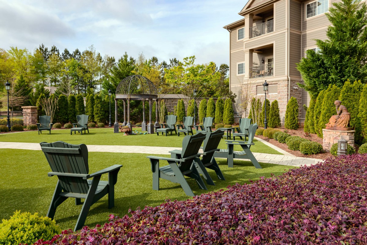 A well-maintained garden with seating areas in front of an apartment building.