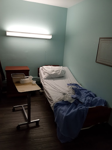 A simple hospital room with a bed and a bedside table.