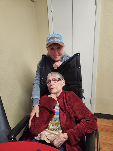 A warm moment shared between a younger woman and an elderly woman sitting in a wheelchair.