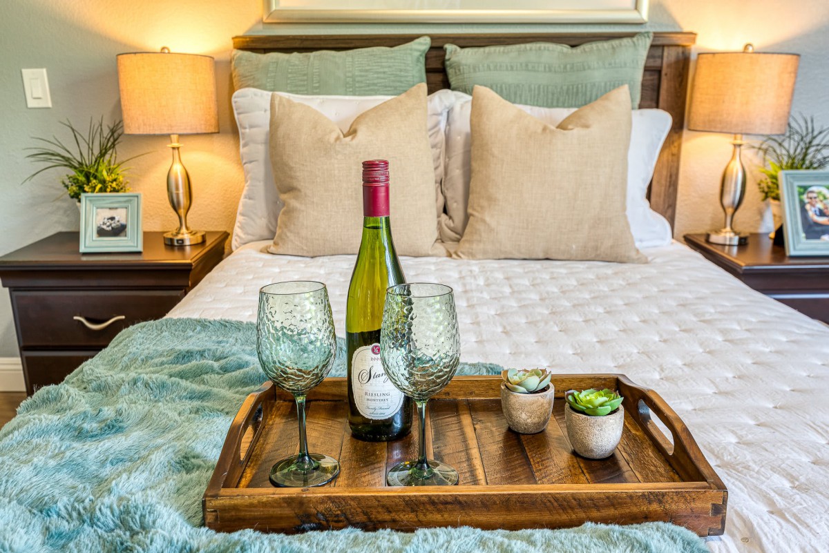 A cozy bedroom setup with a tray holding wine and glasses, perfect for relaxation.