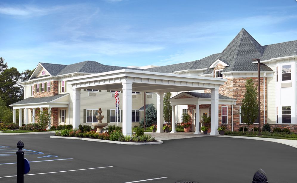 A modern building entrance with prominent columns and a parking area.