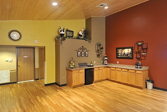 A modern kitchen interior featuring wooden floors and cabinets, with decorative elements on the walls.