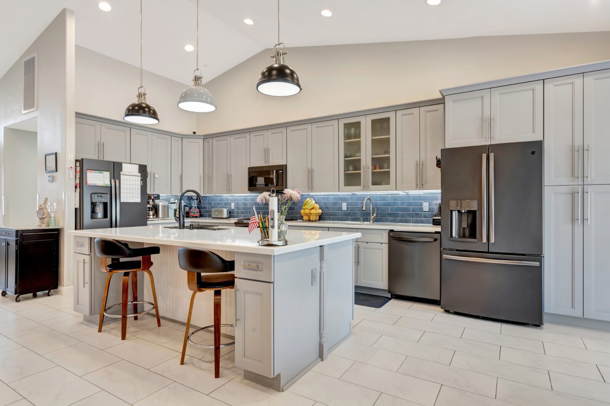 A modern kitchen featuring stainless steel appliances, a central island with bar stools, and elegant pendant lighting.