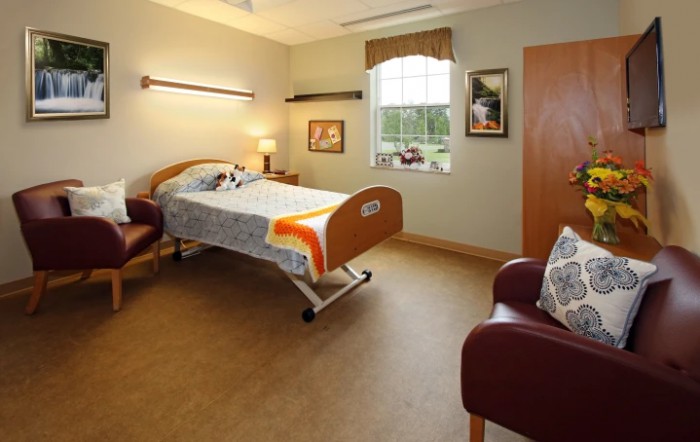 A hospital room with a single bed, chairs, and decor.