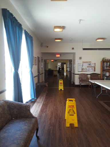 A view of a well-lit lobby area with blue curtains and caution signs on the floor.