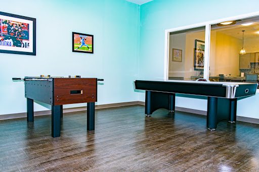 A vibrant game room featuring a foosball table and an air hockey table with blue walls.