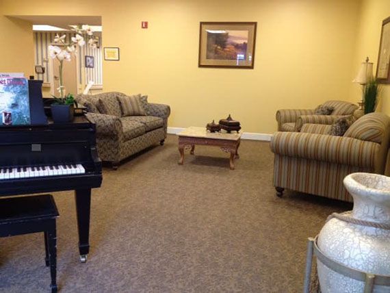 A cozy living room with striped couches, a coffee table, and a piano.
