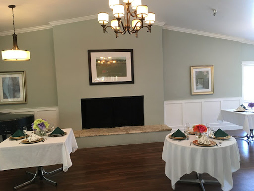 A beautifully arranged dining area featuring elegant tables, a chandelier, and tasteful wall decorations.