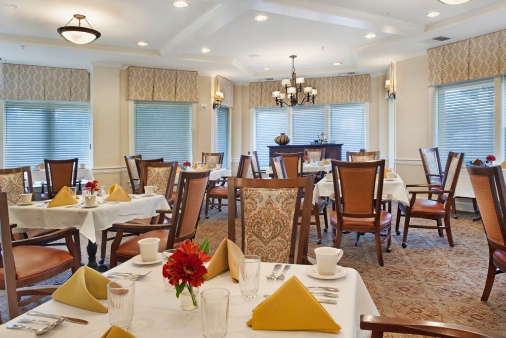 An elegant dining room with neatly set tables and warm lighting.