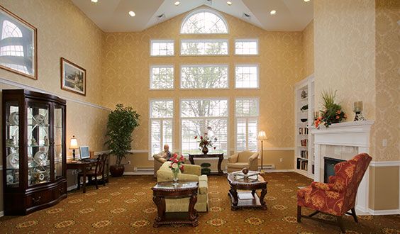 A spacious living room with large windows, elegant furniture, and a high ceiling.