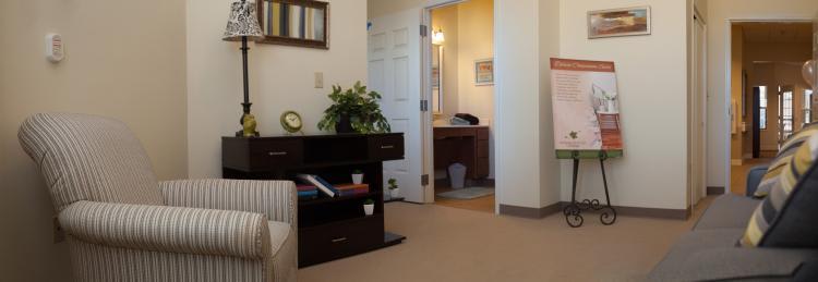 A cozy living room with a bookshelf and a view into an adjacent bathroom.