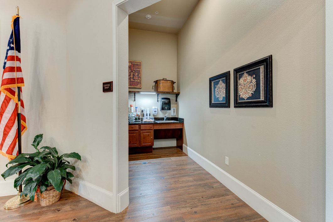 A hallway with wooden flooring, featuring a countertop area and framed artwork on the wall.