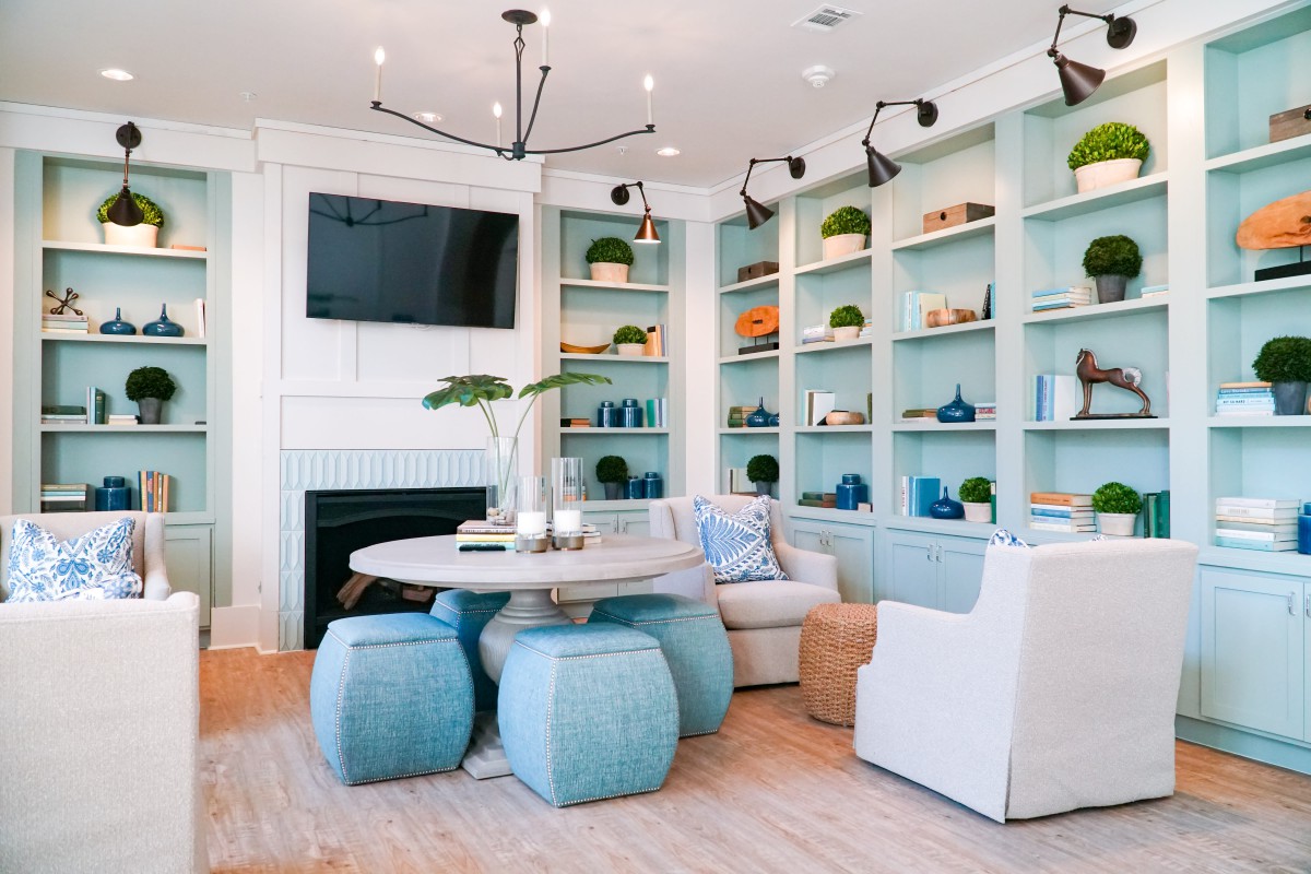 A modern living room with blue accents featuring a central dining table and built-in shelves.