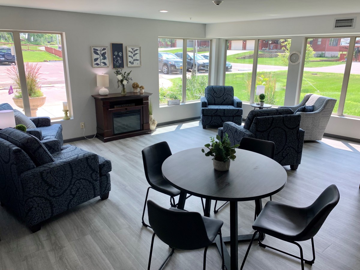 A modern living room with ample natural light, stylish seating, and a cozy fireplace.