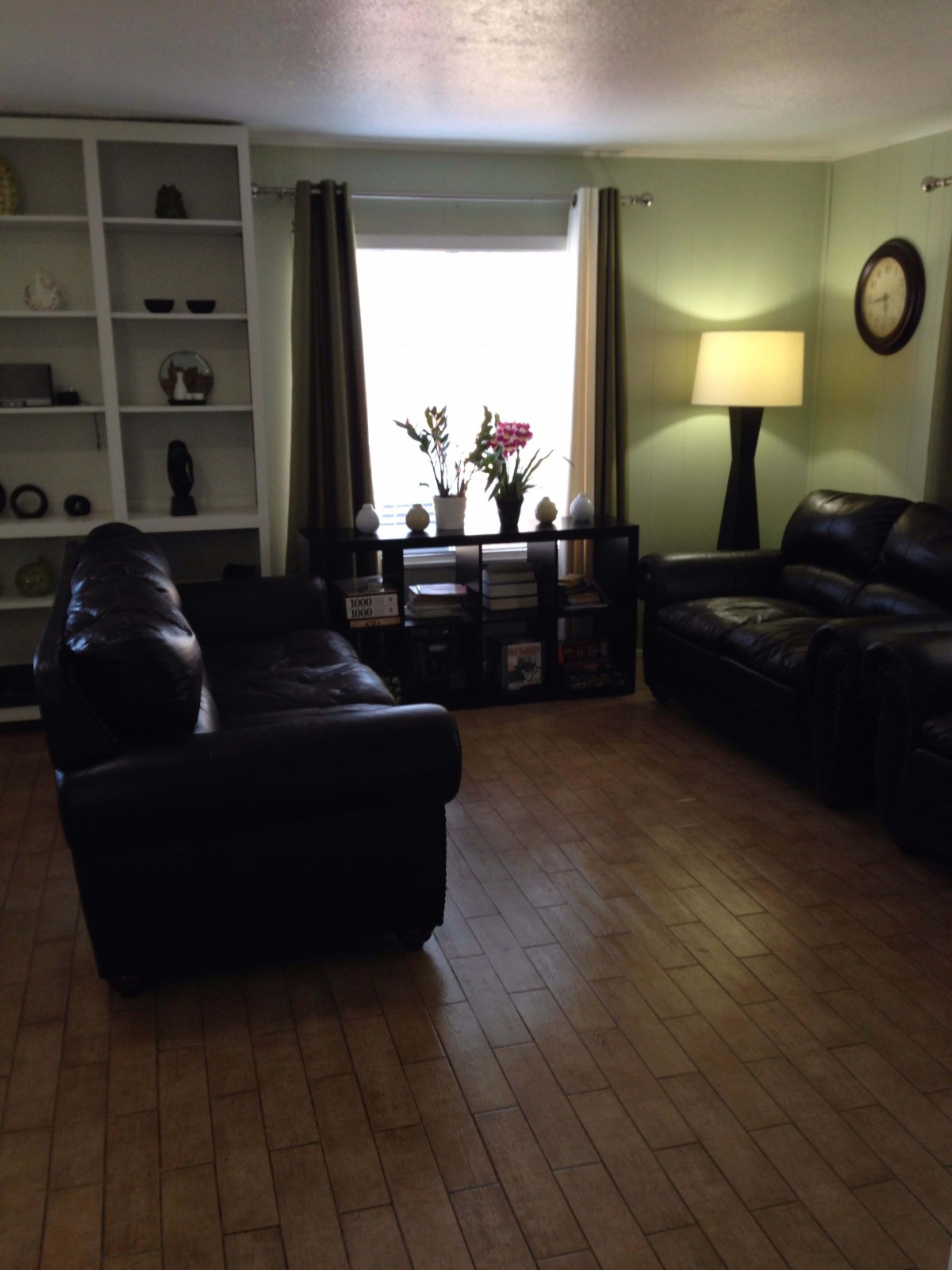 A cozy living room with leather sofas and a floor lamp by the window.