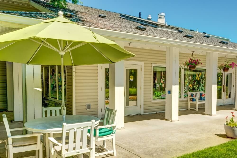 A sunny backyard patio with an umbrella and outdoor furniture.