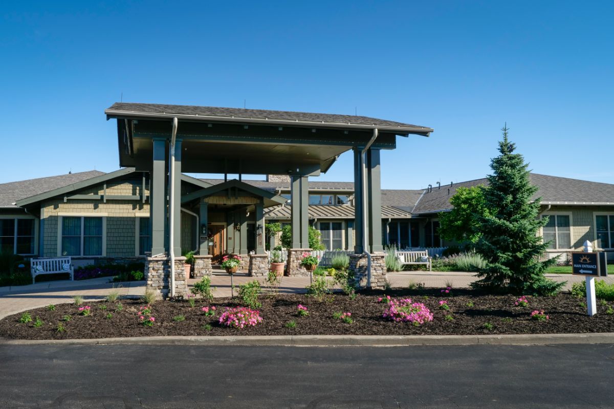 Entrance to a modern building with landscaped garden and covered driveway.