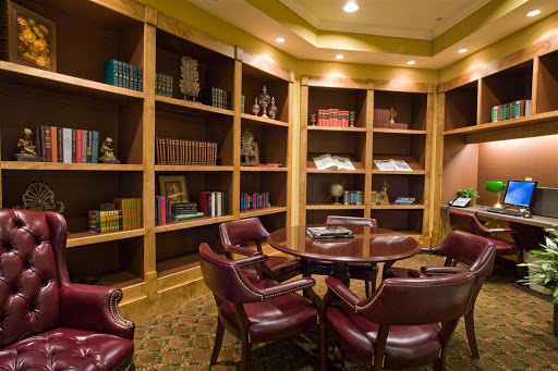 A cozy reading room featuring wooden bookshelves filled with various books and comfortable seating.