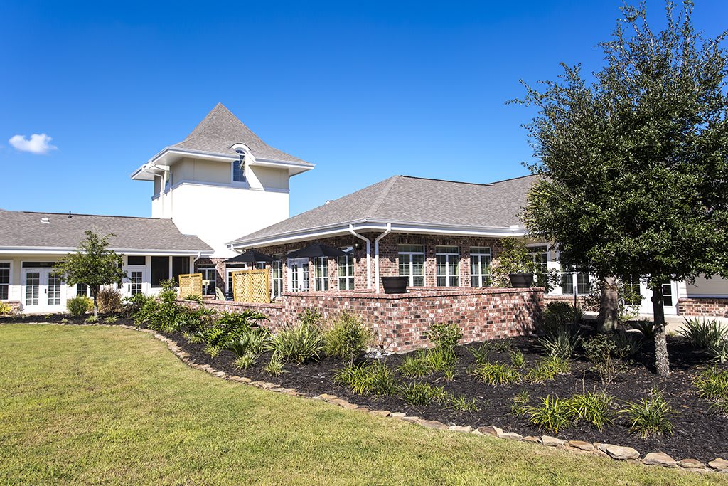 A picturesque building with a tower and landscaped garden under a clear blue sky.