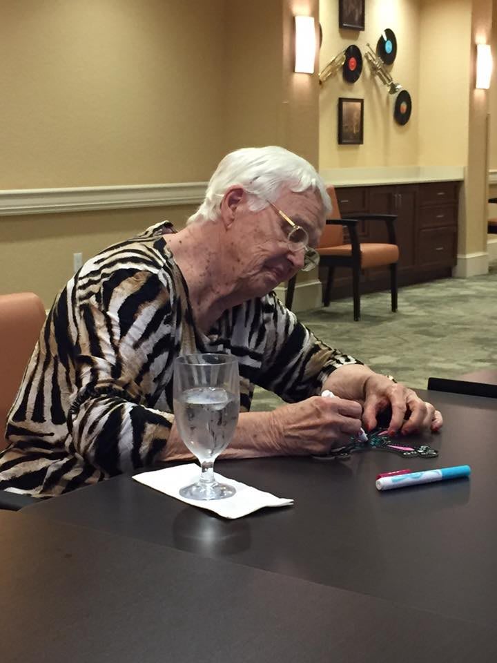 An elderly person wearing a zebra print shirt is signing something at a table indoors.