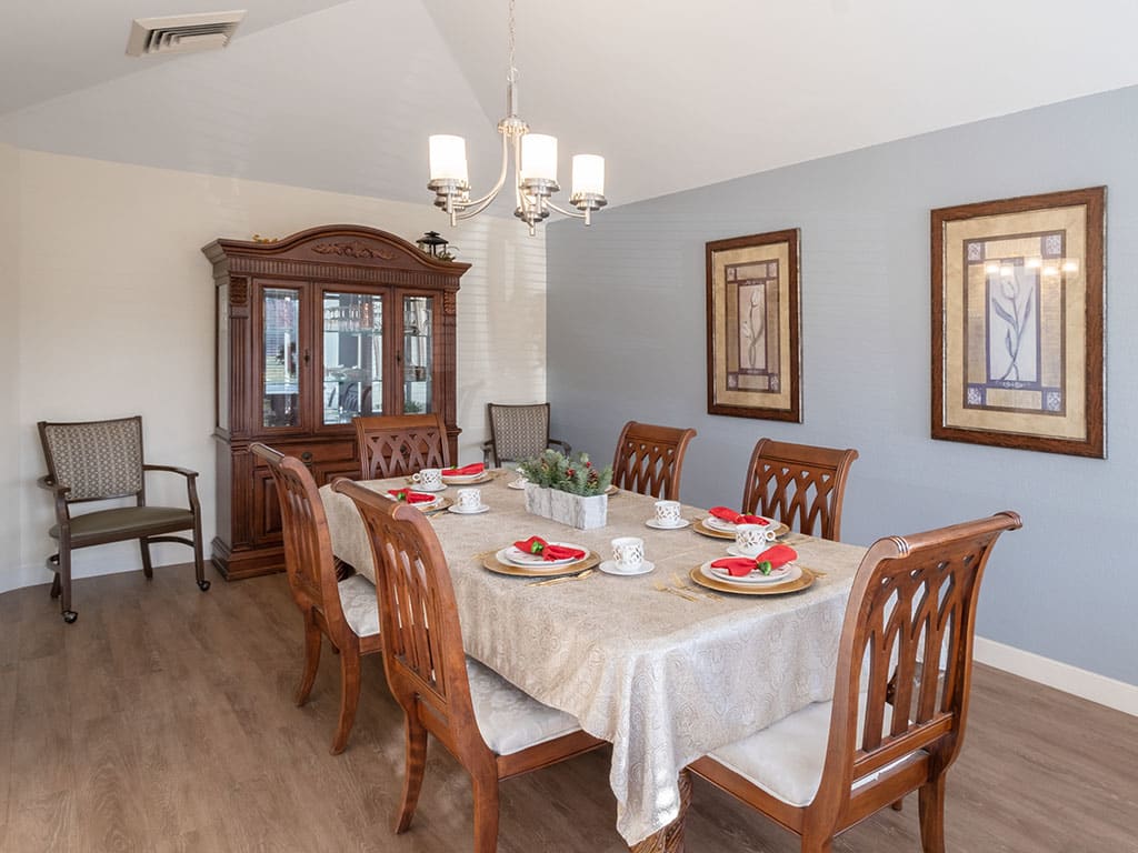 An elegantly decorated dining room with a wooden table set for a meal, complete with a chandelier and china cabinet.