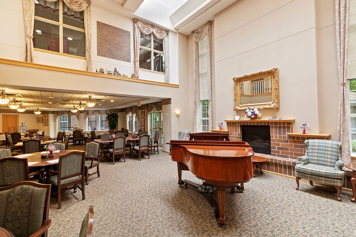 A spacious dining room with a grand piano, fireplace, and elegant seating arrangement.