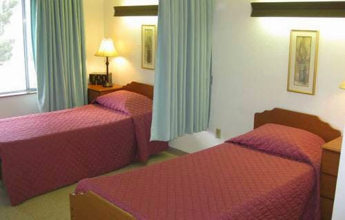 A cozy hotel room featuring twin beds with red bedding and a warm ambiance.