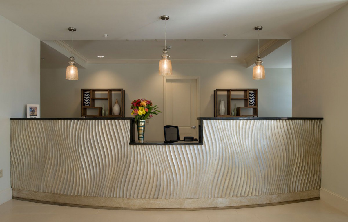 A modern reception desk with decorative lighting and a vase of flowers.