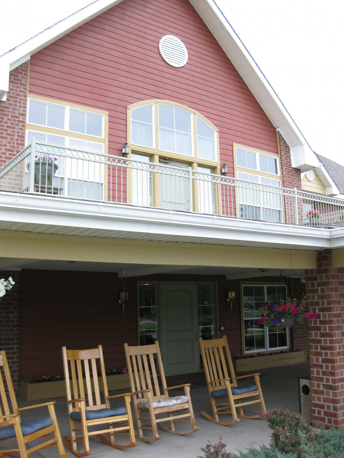 A two-story house with a balcony and rocking chairs on the porch.